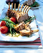 French recipe of rack of lamb with tomatoes, garlic, asparagus and thyme in serving dish