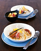 Rice pudding with apple, figs and stewed fruit in bowl on blue plate with spoon