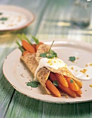Close-up of carrots in sesame crepes and orange sauce garnished with coriander on plate