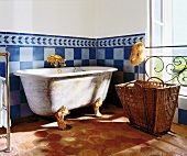 Antike Badewanne auf Löwenfüßen vor einer blau gekachelten Wand