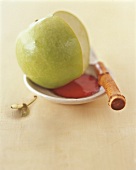 Grüner Apfel auf einem kleinen Teller, daneben ein Messer
