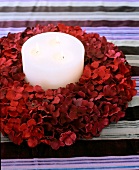 Close-up of candle with three flames in flower wreath on striped velvet fabric