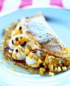Close-up of pancake with caramel, cream and quince pieces on plate
