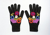 Black gloves embroidered with colourful flowers on white background