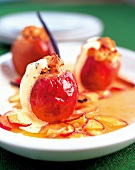 Close-up of stuffed baked apple with custard wine and caramel souse kept on white plate