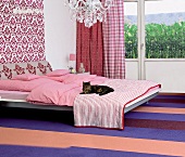 Schlafzimmer in rosé und brombeer Tönen, Bett darauf liegt eine Katze