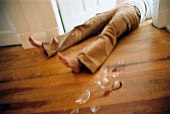 Man lies on floor with broken glass pieces, blurred