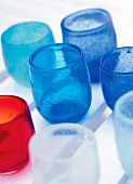 Close-up of blue, red and white coloured juice glasses with small air bubbles
