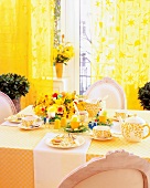 Dining table laid for Easter with yellow flowers, Easter decorations