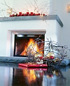 Nest with red and golden baubles in front of fireplace with candles on mantel