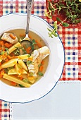 Fish soup with potatoes on plate, overhead view