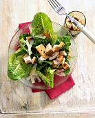 Chicken caesar salad with dressing in glass bowl