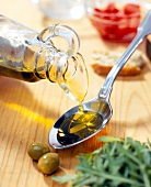 Olive oil being poured from bottle on spoon