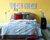 Bed with pillows decorated with patterned tiles on yellow wall