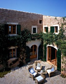 Courtyard with wicker furniture and overgrown ivy on walls in Mallorca, Spain