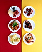 Six plates of appetizers such as patatas bravas, cheese and ham, chorizo, dates and bacon