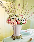 Barbara branches and spring bouquet in pink antique vase on table