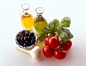 Olive oil, tomatoes, basil, garlic and black olives on white background