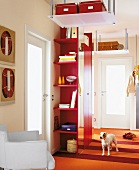 Red hallway with shelves and dog on stairs in living room