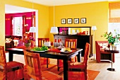 Esszimmer in Orange und Schwarz: dunkler Holztisch, Stühle mit Hussen