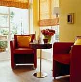 Rote Sessel mit gelben Kissen, rund. Beistelltisch am Fenster, Wand gelb
