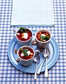 Three cup of tomato soup with cream and croutons on plate