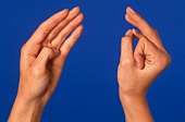 Close- up of woman's hand performing acupressure mudra against blue background