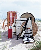 Picnic accessories like carry bag, thermos, fish holder and cushion on sand dune