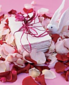 Bundled of handmade paper wrapped with red ribbon, toy bird and rose petals