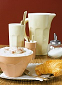 Cup of coffee with milk froth served with croissant