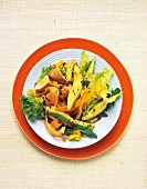 Bowl of avocado salad with chicken breast on orange plate, overhead view