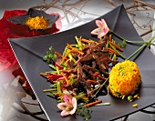 Beef with vegetables and spicy chili sauce with rice on black square dish