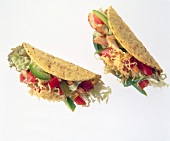 Close-up of mini-taco with chicken, avocado, beans, pepper and lettuce on white background