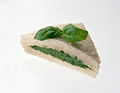 Close-up of spinach sandwich with basil on white background