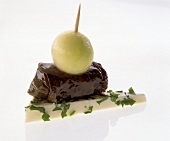 Close-up of vine leaves and melon balls on feta cheese on white background