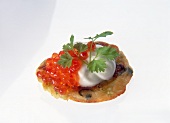 Close-up of fresh cream and trout caviar on vegetable buffer on white background