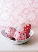 Two scoops of currant ice cream with red berries in serving dish