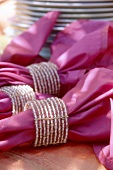 Pinkfarbene Servietten, Servietten- ringe aus Perlenbändern
