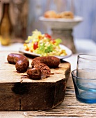 Close-up of sliced lamb sausages on wooden block