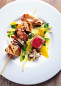 Close-up of seafood skewers with orange and fennel salad on plate