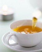 Close-up of tea being poured in white cup with saucer