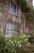 Great Dixter House: graue Wand eines Landhauses, davor bunte Blumen