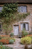 Great Dixter House: Eingangstür e. Landhauses, davor rote Blumen