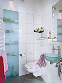 Badezimmer in weiß mit Glaswaschbecken und Glasschranktür