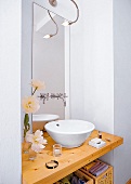 Waschbecken, ähnlich einer Schüssel steht auf einer Holzplate im Bad
