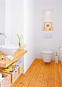 Helles Badezimmer mit Holzfußboden und Holzablage für das Waschbecken