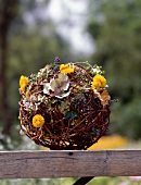 Braided ball with flowers and leaves on wood