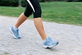 Close-up of woman walking on road wearing sneakers