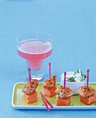 Chicken and melon slices in skewers on plate with melon drink in martini glass