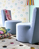 Blue cocktail chair on woolen carpet against wallpaper with colourful circles